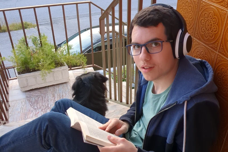 A white guy (me) reading a book, alongside his black Dog