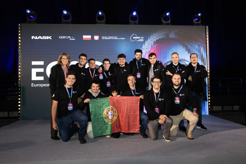 15 people posing for a team portrait, holding a Portuguese flag